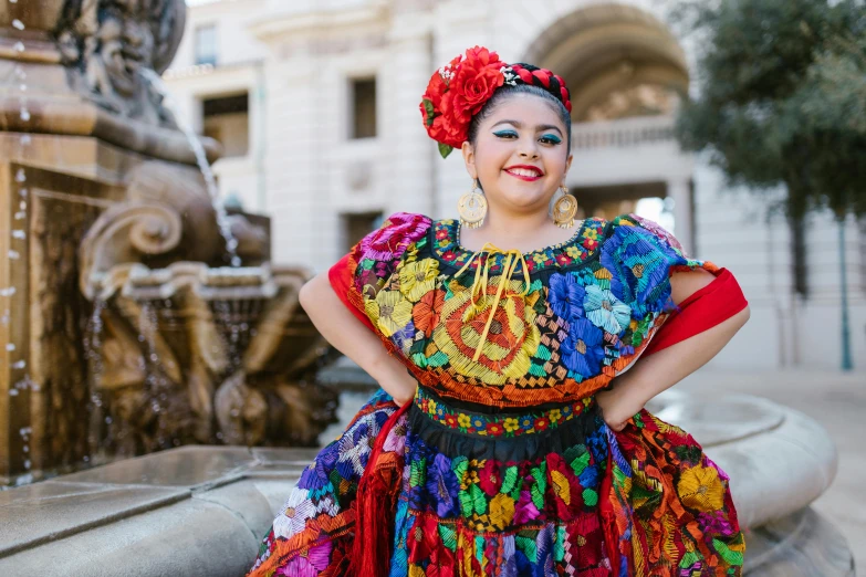 a woman in a colorful dress standing in front of a fountain, wearing authentic attire, latino features, plus-sized, colorful uniforms