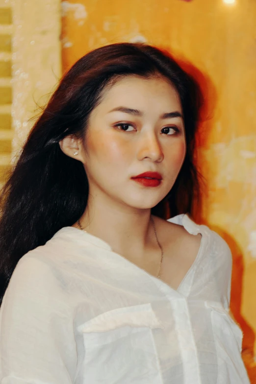 a woman standing in front of a yellow wall, an album cover, inspired by Ai Xuan, pexels contest winner, lips slightly parted, gongbi, grainy low quality, high angle closeup portrait