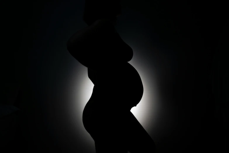a pregnant woman standing in the dark, an album cover, inspired by Robert Mapplethorpe, pexels contest winner, moon backlight, leaked photo, silhouette :7, bouncy belly
