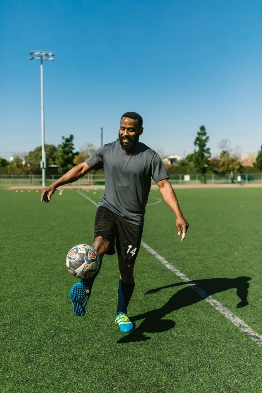 a man kicking a soccer ball on a field, bay area, kevin hart, working out, teaching