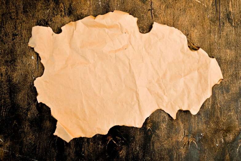 a piece of paper sitting on top of a wooden table, leathery, background image, mapbox, paper cutout