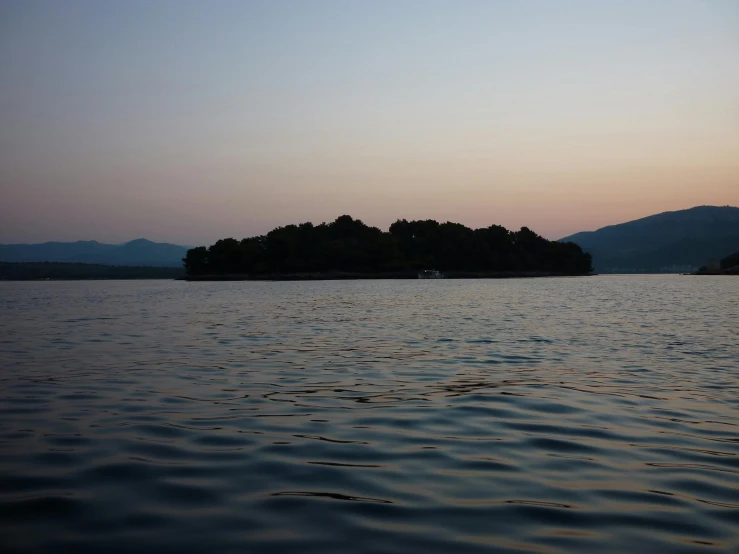 a small island in the middle of a large body of water, evening time, with mountains in the distance, aketan, atmospheric photo