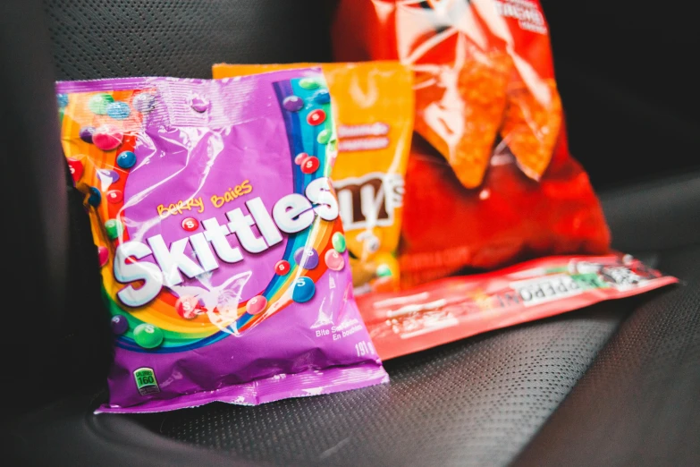 a couple of bags of candy sitting on top of a car seat, by Julia Pishtar, snacks, fan favorite, skydsgaard, drink