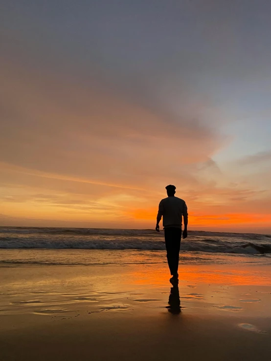 a man standing on top of a beach next to the ocean, during a sunset, profile image