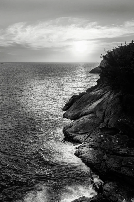 a black and white photo of the ocean, cliff side at dusk, sunset kanagawa prefecture, cinq terre, ((sunset))