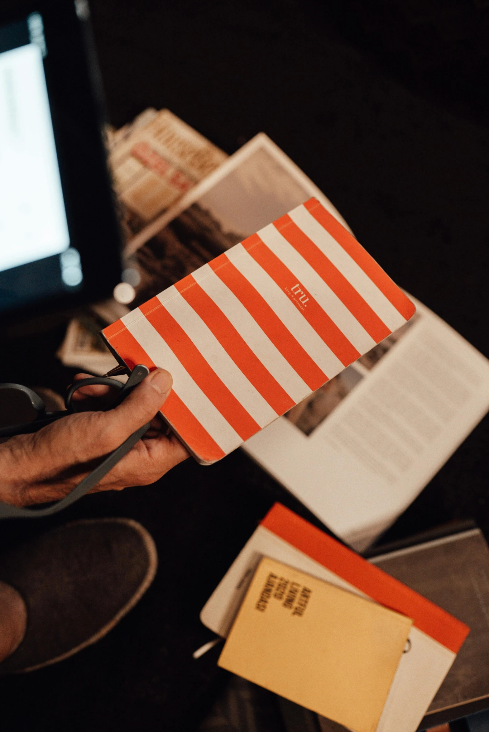 a person using a pair of scissors to cut a piece of paper, an album cover, pexels contest winner, orange racing stripes, holding notebook, candid photograph, striped