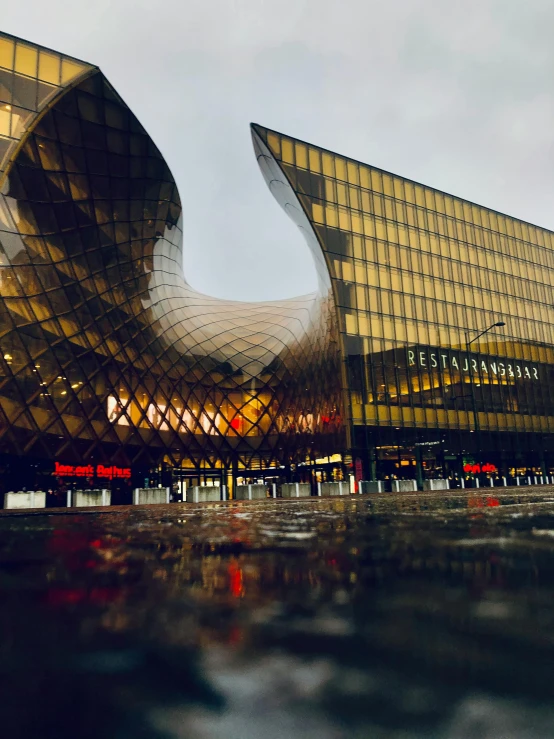 a reflection of a building in a puddle of water, inspired by Zha Shibiao, unsplash contest winner, on a futuristic shopping mall, vibrant but dreary gold, hannover, seen from outside