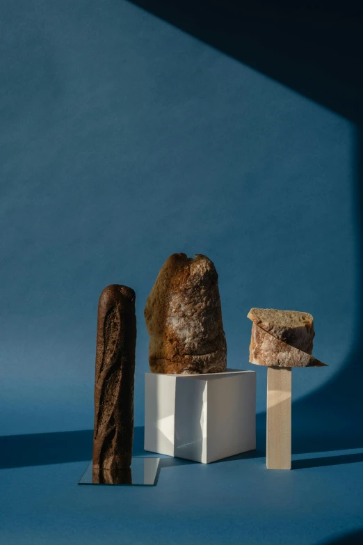 a couple of pieces of bread sitting on top of a table, an abstract sculpture, unsplash, visual art, mineral collections, tall, holding a baguette, varying angles