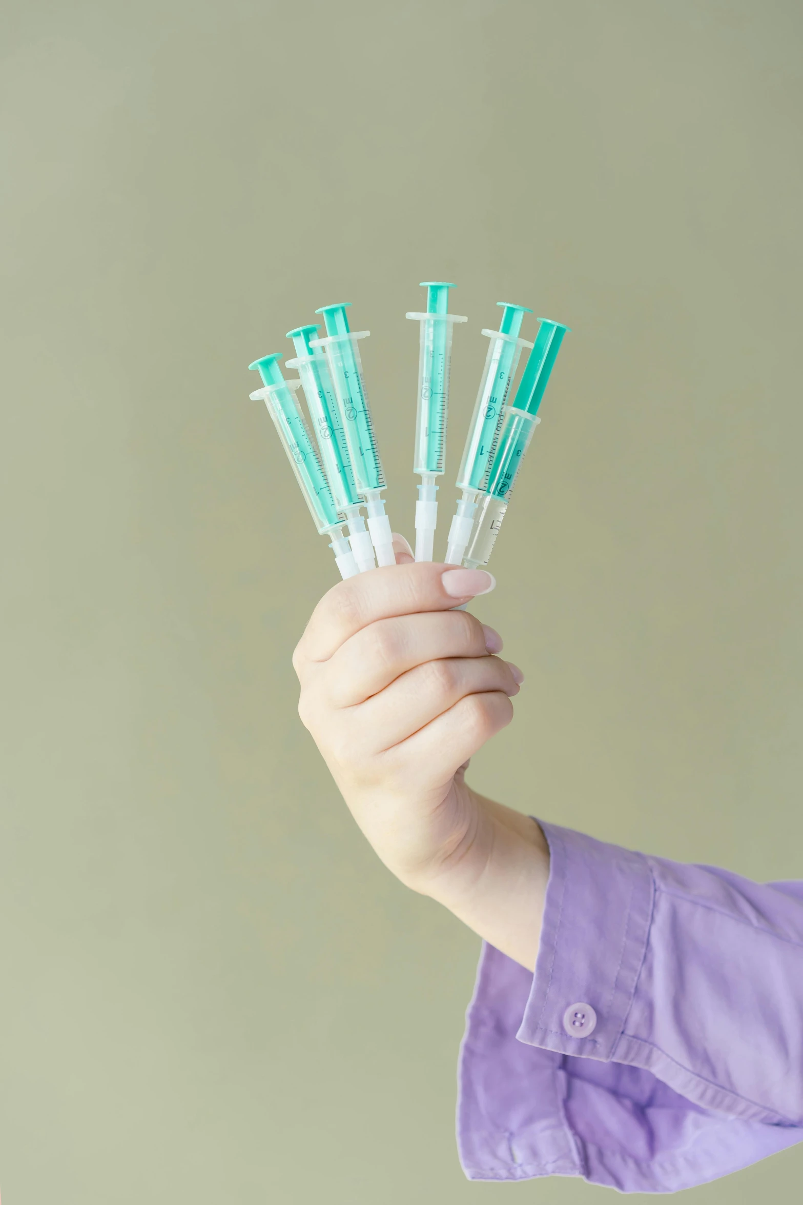 a close up of a person holding a bunch of sylls, syringes, full product shot, teal aesthetic, made of lab tissue