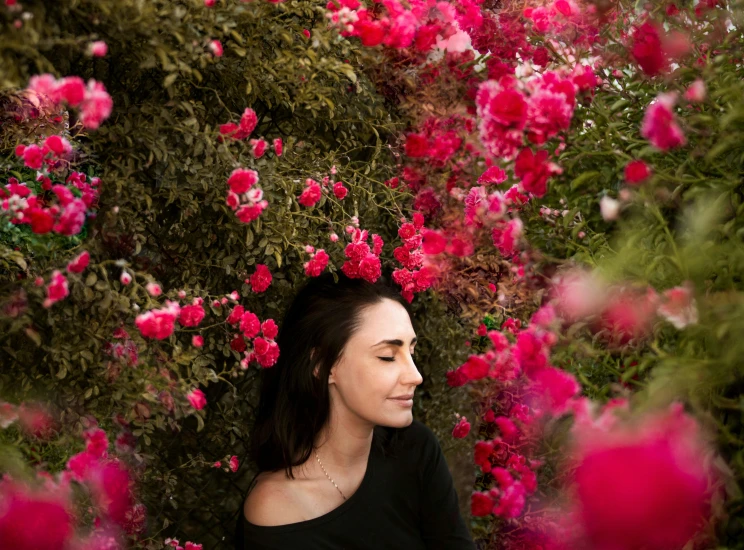 a woman standing in front of a bush of pink flowers, by Julia Pishtar, pexels contest winner, laying on roses, avatar image, profile image, candid portrait photo