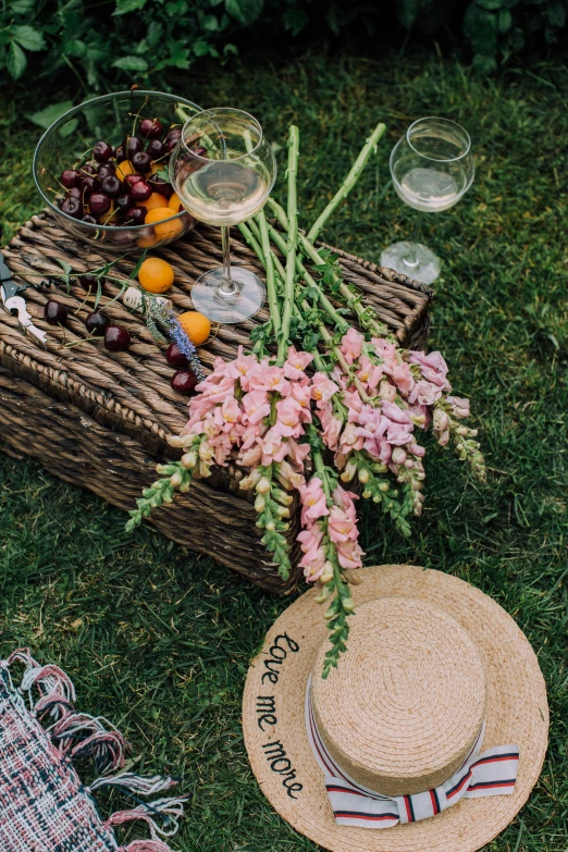 a basket filled with flowers sitting on top of a lush green field, wine, sitting on one knee on the grass, flatlay, offering a plate of food