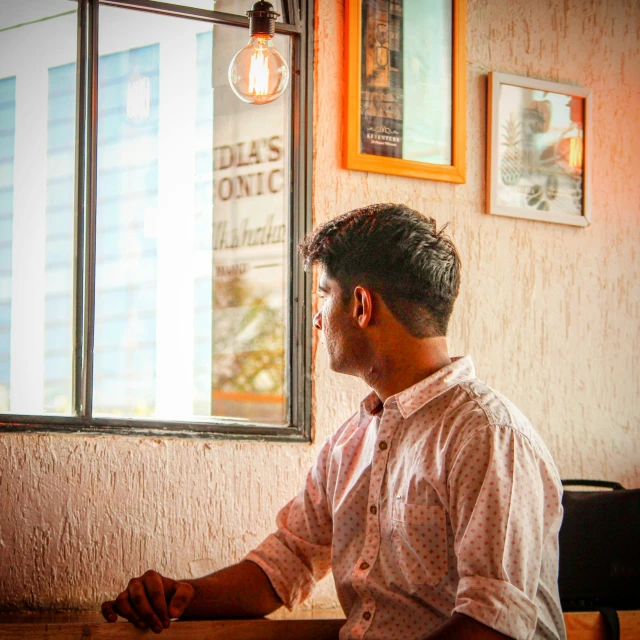 a man sitting at a table in front of a window, pexels contest winner, jayison devadas, sitting at the bar, profile image, vinayak