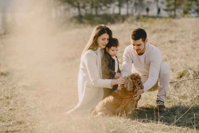 a man and woman kneeling in a field with a dog, pexels contest winner, husband wife and son, avatar image, maintenance, pet animal