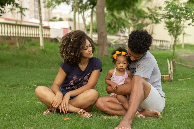 a couple of people that are sitting in the grass, by Fernando Gerassi, pexels, renaissance, 3 5 year brazilian mother, afro hair, portrait of family of three, perfect android girl family