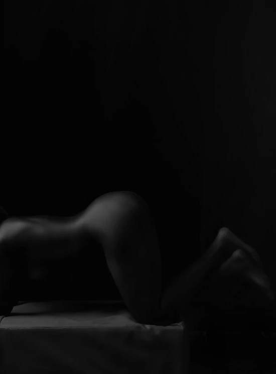 a naked woman laying on a bed in the dark, inspired by Robert Mapplethorpe, unsplash, black skin!!!, back view. nuri iyem, 2017, smooth curves