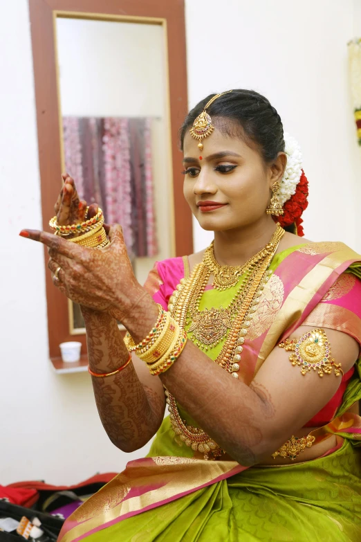 a woman in a green sari sitting on a bed, intricate gold jewlery, wearing a wedding dress, 2 5 6 x 2 5 6 pixels, gloves and jewelry. motion