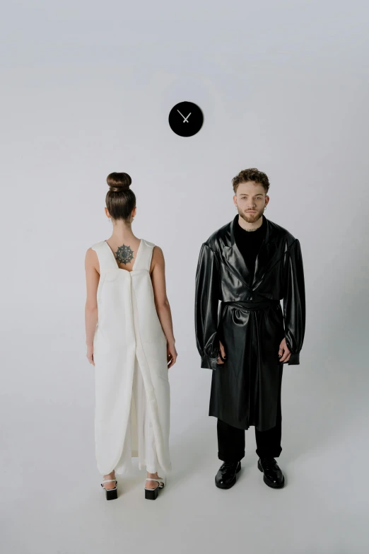 a man and a woman standing next to each other, an album cover, inspired by Jonas De Ro, wearing black leather trenchcoat, tech robes, hybrid human/tank, offwhite