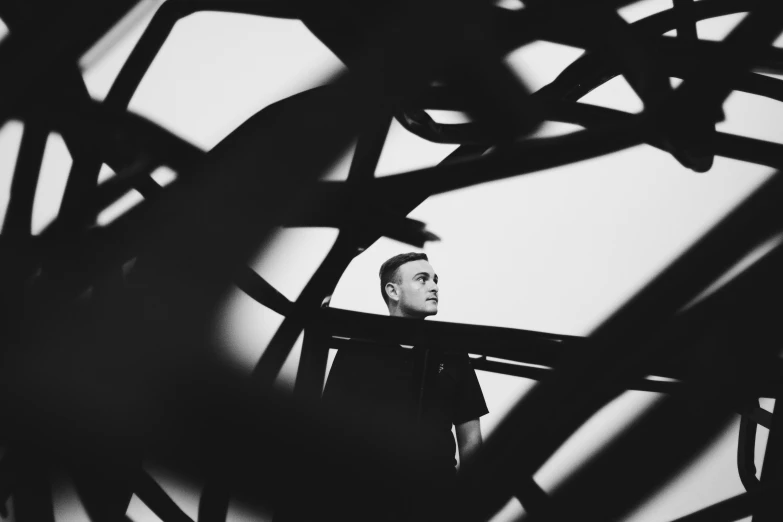 a man standing in front of a sculpture, a black and white photo, pexels contest winner, flume cover art, portrait image, mac miller, bridge