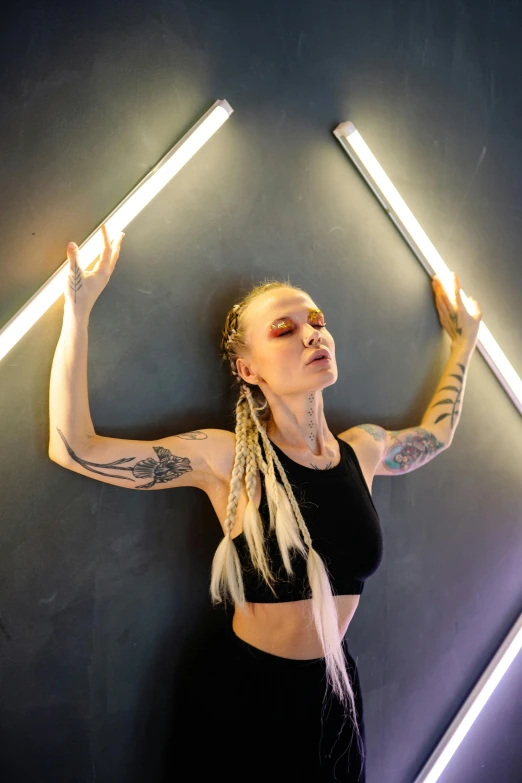 a woman standing in front of a wall with neon lights, a tattoo, inspired by Louisa Matthíasdóttir, light and space, yoga, suspended in zero gravity, lightweight, nightclub dancing inspired