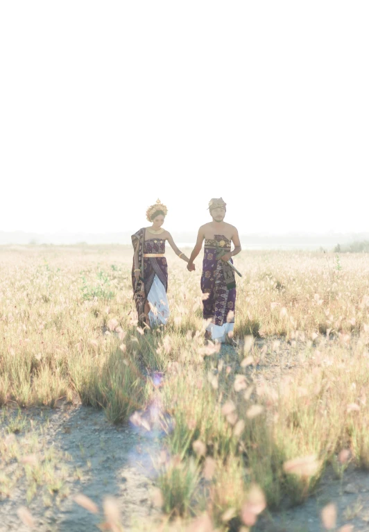 two women walking through a field holding hands, trending on unsplash, happening, somali attire, bali, portra, mermaids in distance