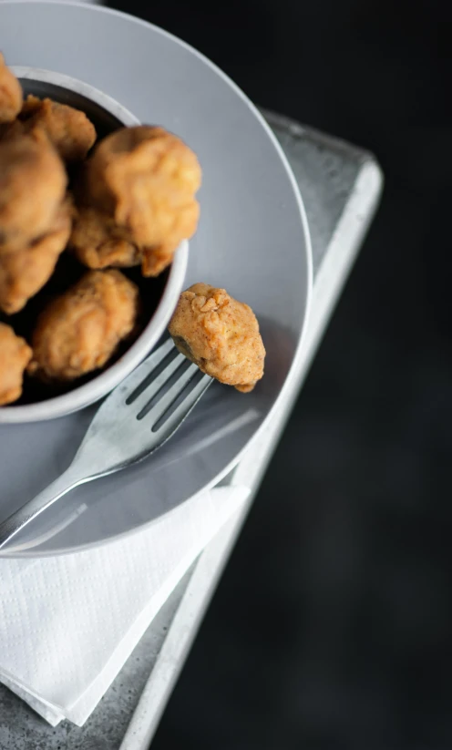 a white plate topped with tater tots next to a fork, unsplash, renaissance, flying saucers, high quality photo, square, grey