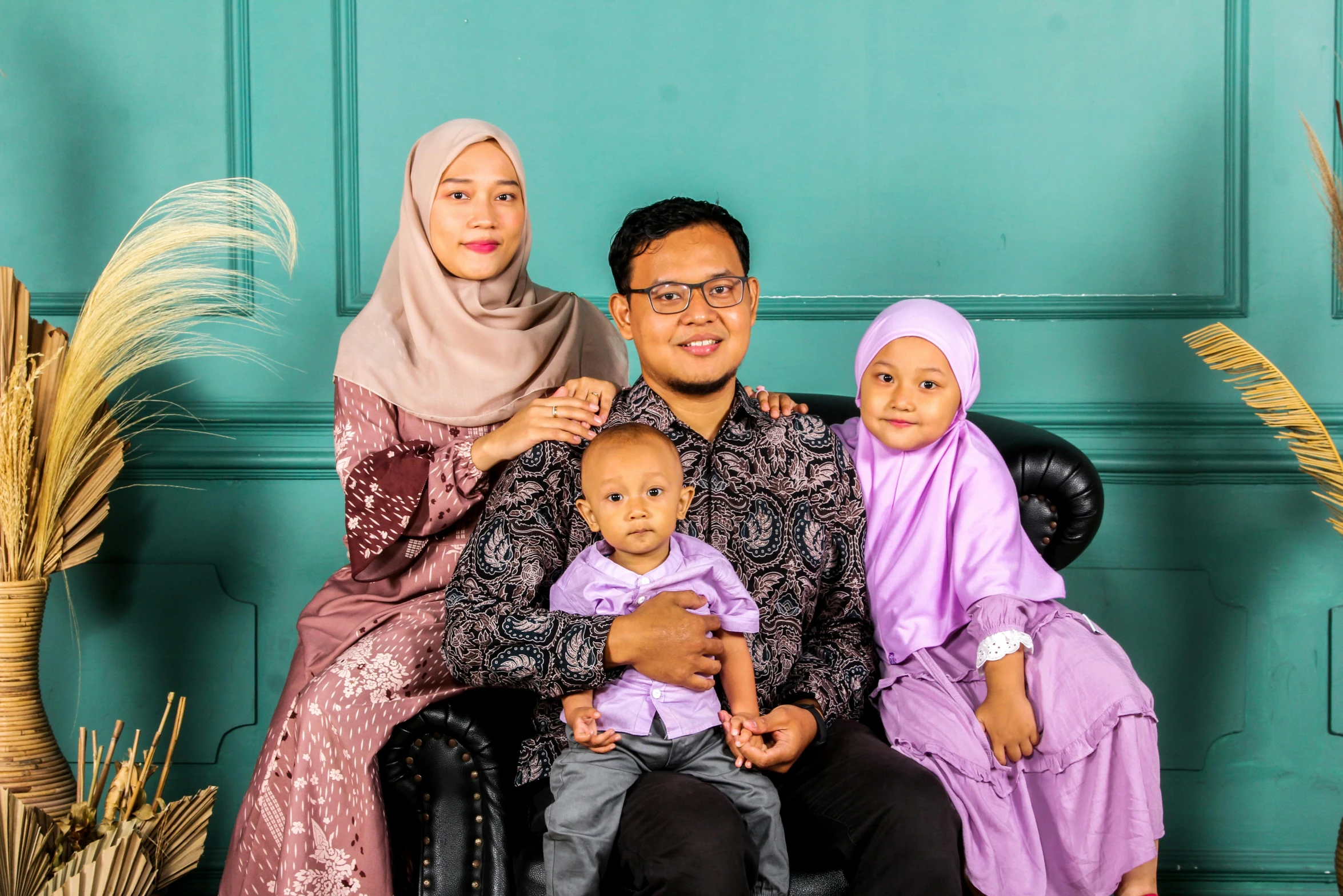 a family posing for a picture in front of a green wall, a picture, by Basuki Abdullah, pexels contest winner, hurufiyya, caring fatherly wide forehead, square, modestly dressed, studio 4 k