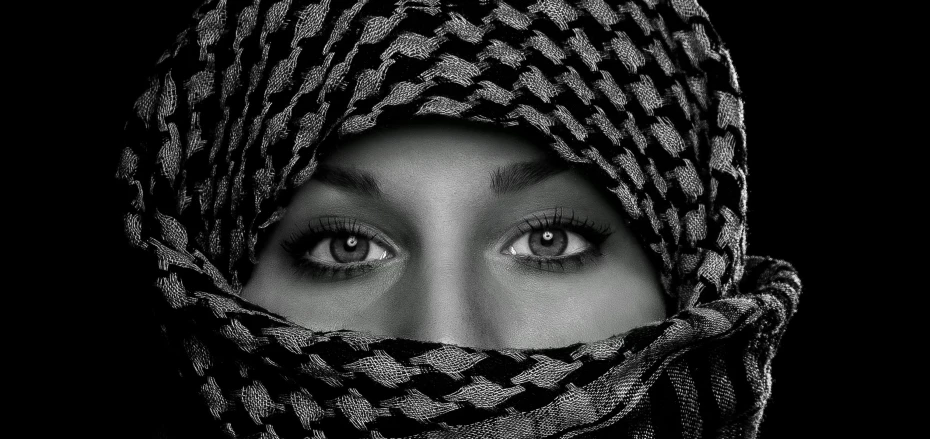 a black and white photo of a woman wearing a headscarf, a black and white photo, trending on pexels, !!!!! human eyes!!!!!!, new album cover, arab princess, hunter eyes