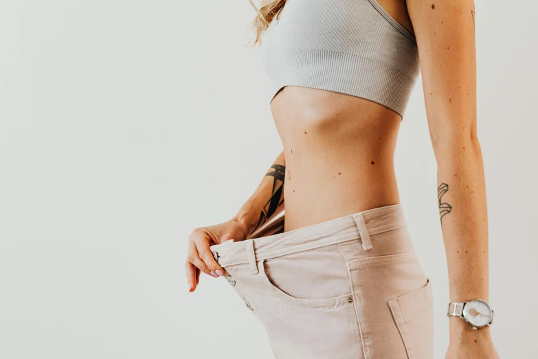 a woman standing with her hands in her pockets, a tattoo, trending on pexels, physical : tinyest midriff ever, background image, scales, pink body