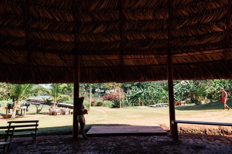 a person standing under a thatched roof, wide open space, ayahuasca ceremony, profile image