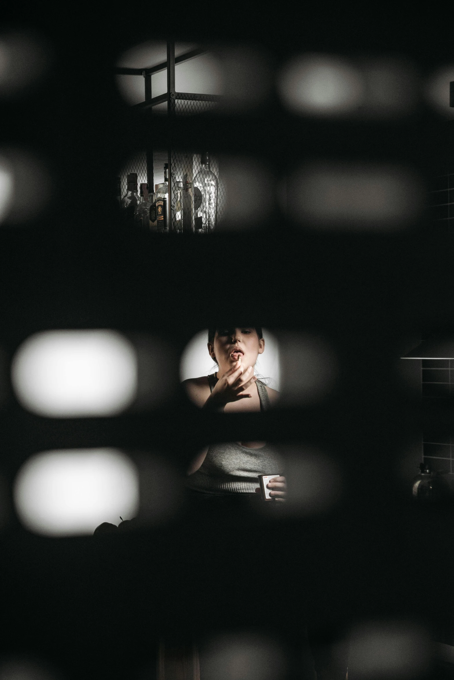a man that is standing in front of a mirror, pexels contest winner, light and space, the woman is behind bars, drinking, spotlight from above, low iso