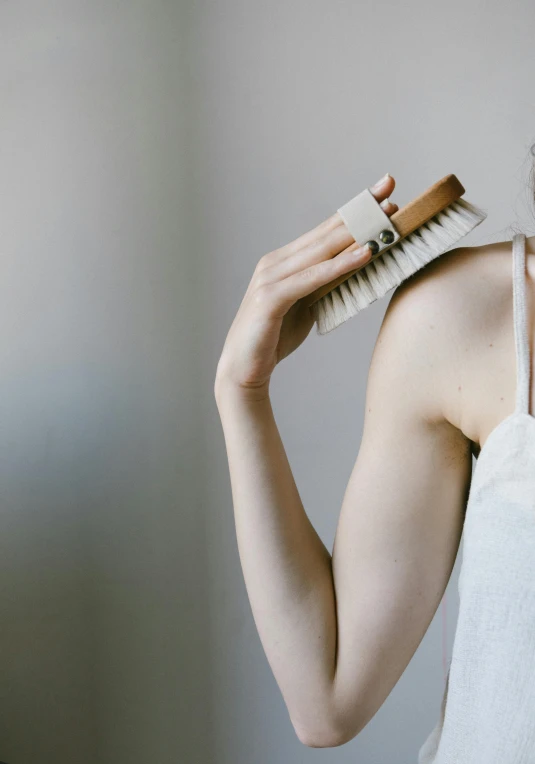 a woman brushing her hair with a brush, unsplash, renaissance, perfect body face and hands, holding a wood piece, dezeen, white