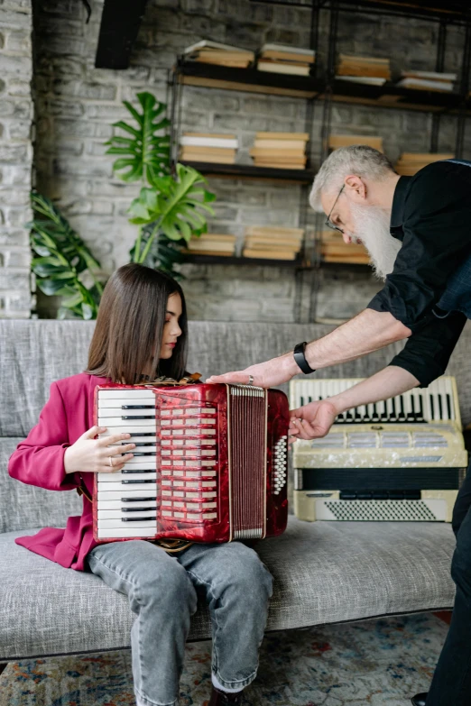 a man playing an accordion next to a woman sitting on a couch, an album cover, by Julia Pishtar, pexels contest winner, renaissance, inspect in inventory image, synthesizers, maroon, youtube thumbnail