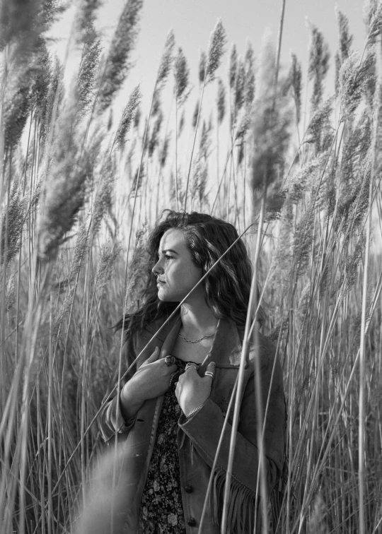 a woman standing in a field of tall grass, inspired by Max Dupain, 🤤 girl portrait, 4k greyscale hd photography, reeds, curls and curves