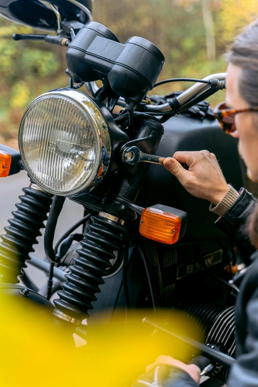 a woman in a leather jacket working on a motorcycle, by Lee Loughridge, unsplash, led indicator, rectangle, yellow, wiring