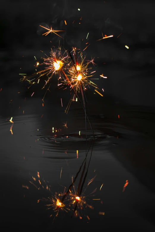 a couple of sparklers that are in the water, a picture, pexels, conceptual art, paul barson, magical stormy reflections, shining gold and black and red, happy birthday