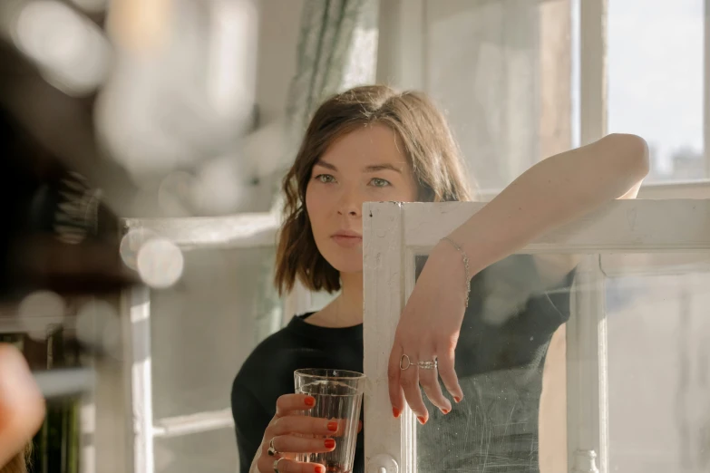 a woman holding a glass in front of a window, inspired by Elsa Bleda, pexels contest winner, photorealism, milla jovovich, anya taylor joy, ignant, jewelry