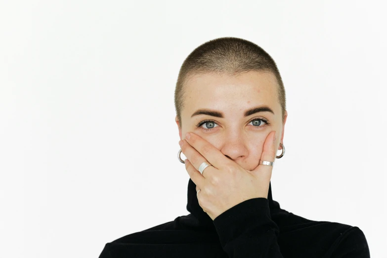a woman covering her face with her hands, an album cover, antipodeans, buzz cut, white backdrop, hand on his cheek, without text