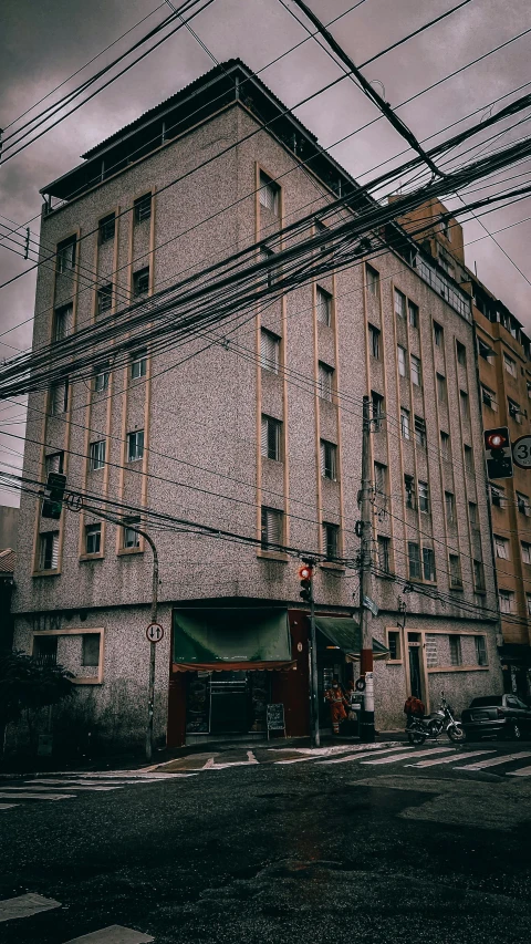 a tall building sitting on the side of a road, inspired by Elsa Bleda, unsplash, art nouveau, exposed wires, low quality photo, 90s japan, grainy photo