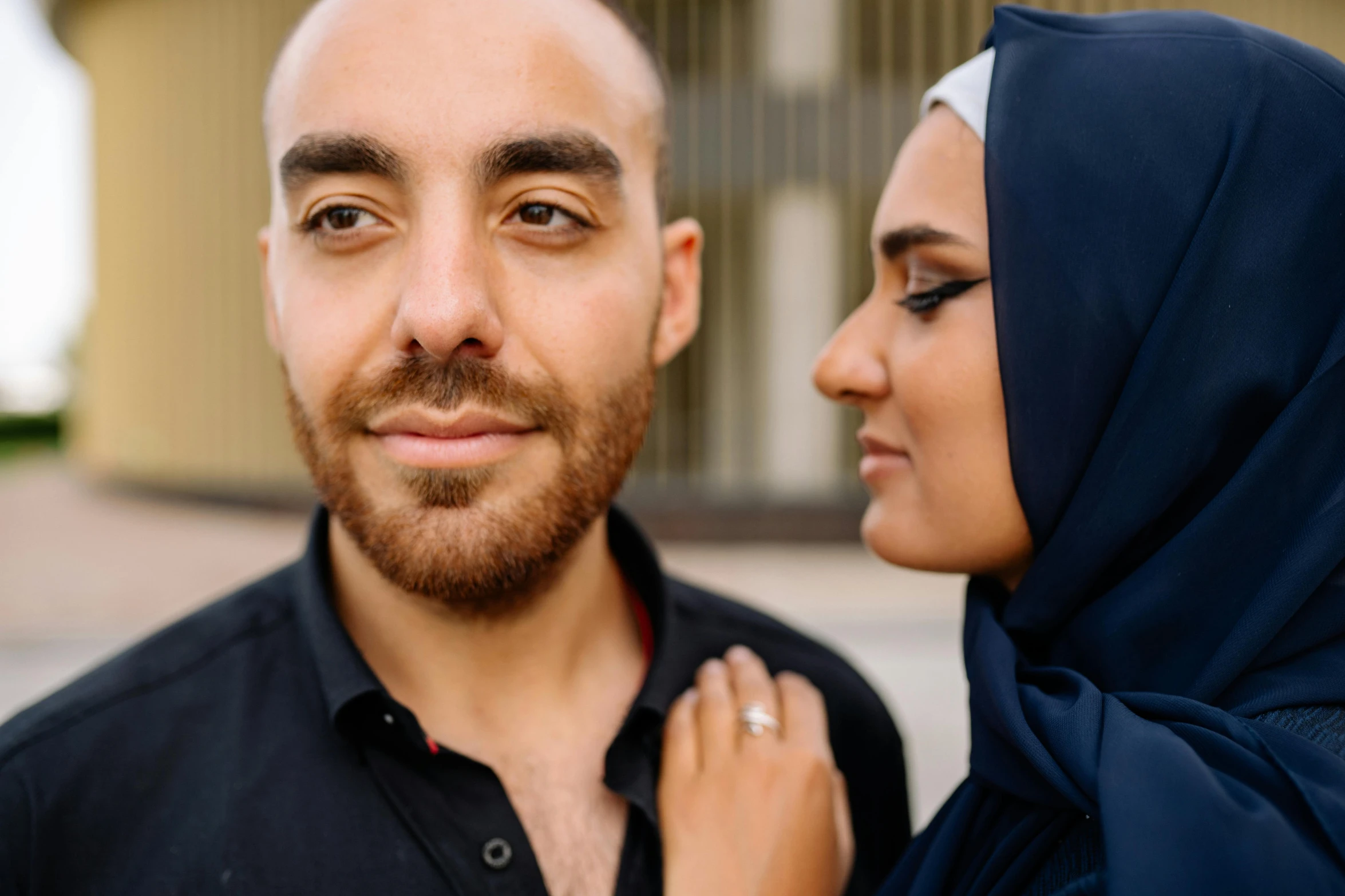 a man standing next to a woman wearing a hijab, by Julia Pishtar, pexels contest winner, hurufiyya, wearing a dark blue polo shirt, middle eastern skin, man and woman in love, shaven