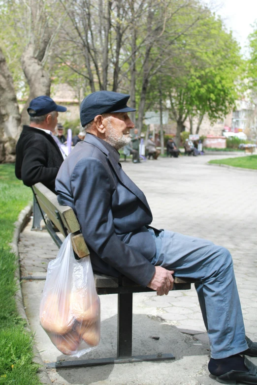 a couple of men sitting on top of a bench, aging, in a square, color photo, illustration »