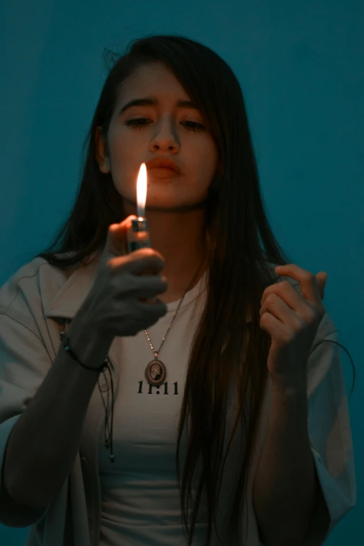a woman holding a lit candle in front of her face, an album cover, inspired by Elsa Bleda, trending on pexels, smoking a pipe, woman in streetwear, teenager girl, hindu aesthetic