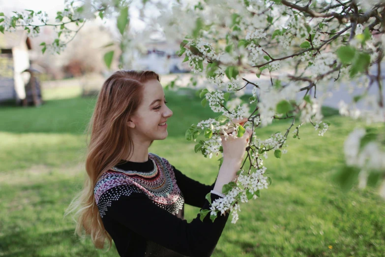 a woman standing under a tree with white flowers, by Julia Pishtar, pexels contest winner, cute young redhead girl, perfect spring day with, celebrating, college