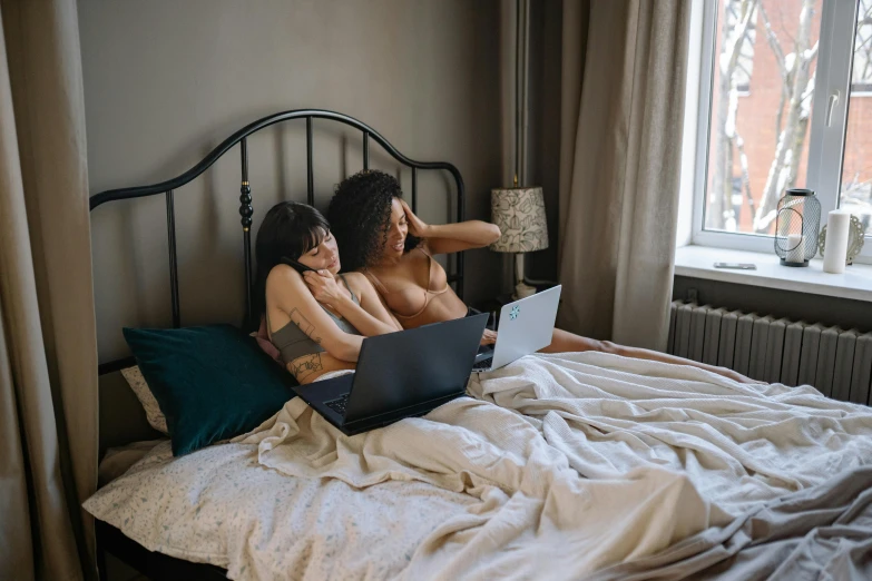 a couple of women sitting on top of a bed with a laptop, trending on pexels, wearing nothing, 6 : 3 0 am, open belly, everything fits on the screen