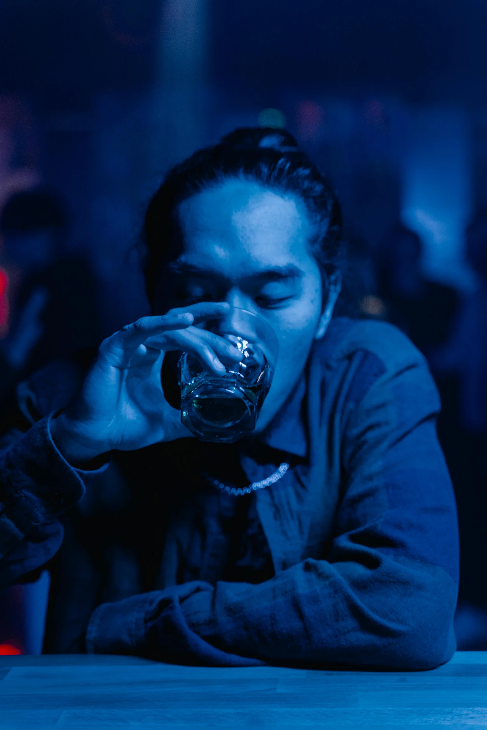 a man sitting at a table drinking from a glass, a portrait, inspired by Liam Wong, unsplash, nightclub, joe taslim, blue, performance