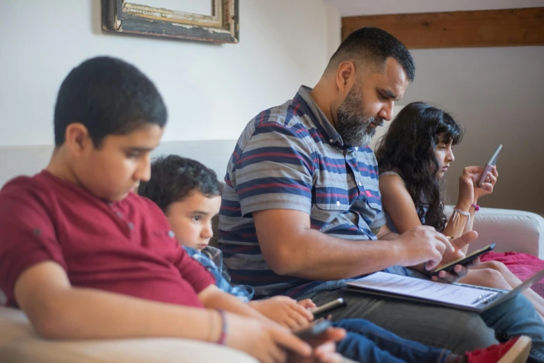 a group of people sitting on top of a couch, by Dan Content, pexels, hurufiyya, sitting at a computer, assyrian, family, looking at his phone