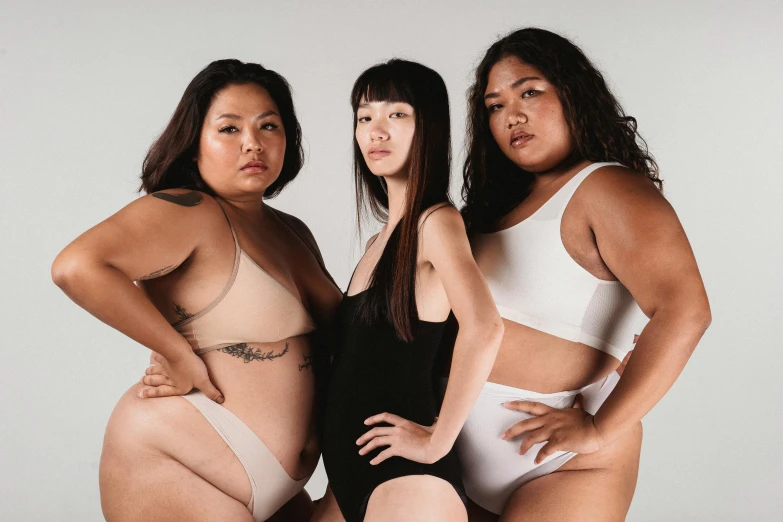 a group of three women standing next to each other, inspired by Vanessa Beecroft, unsplash, half asian, big stomach, wearing leotard, thick linings