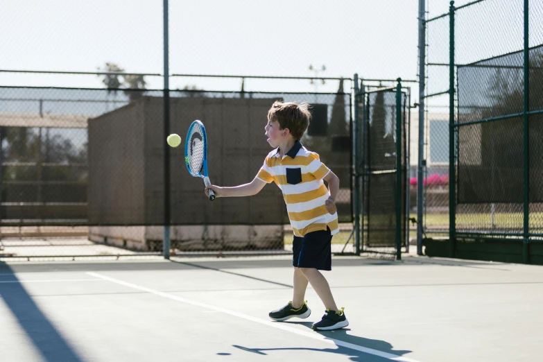 a young boy holding a tennis racquet on a tennis court, a picture, by Joe Bowler, pexels contest winner, action shot, 4yr old, panels, principal set photography