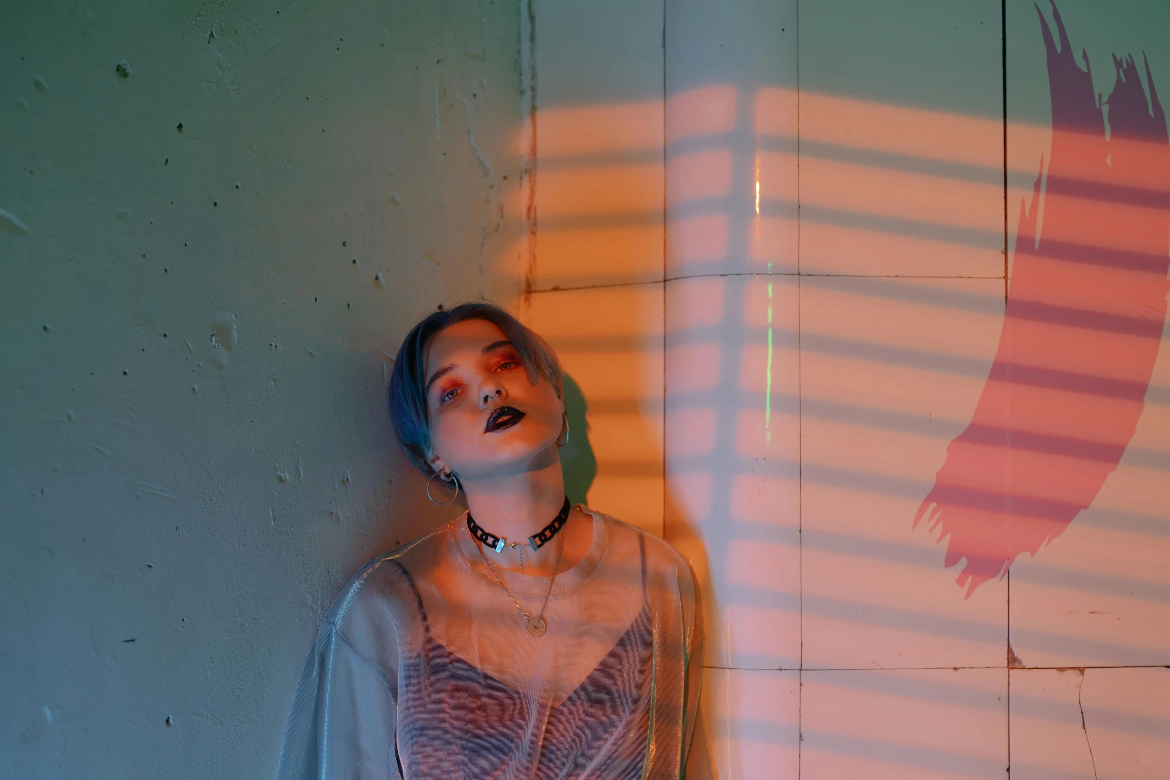 a woman that is standing in front of a wall, an album cover, inspired by Elsa Bleda, trending on pexels, androgynous vampire, glowing with silver light, colorful aesthetic, loish |