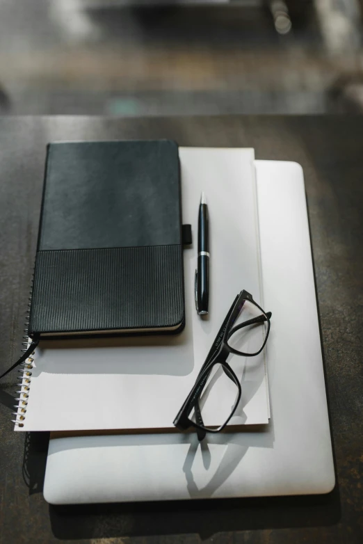 an open notebook sitting on top of a table next to a pair of glasses, unsplash, paul barson, black marker, plush leather pads, background image