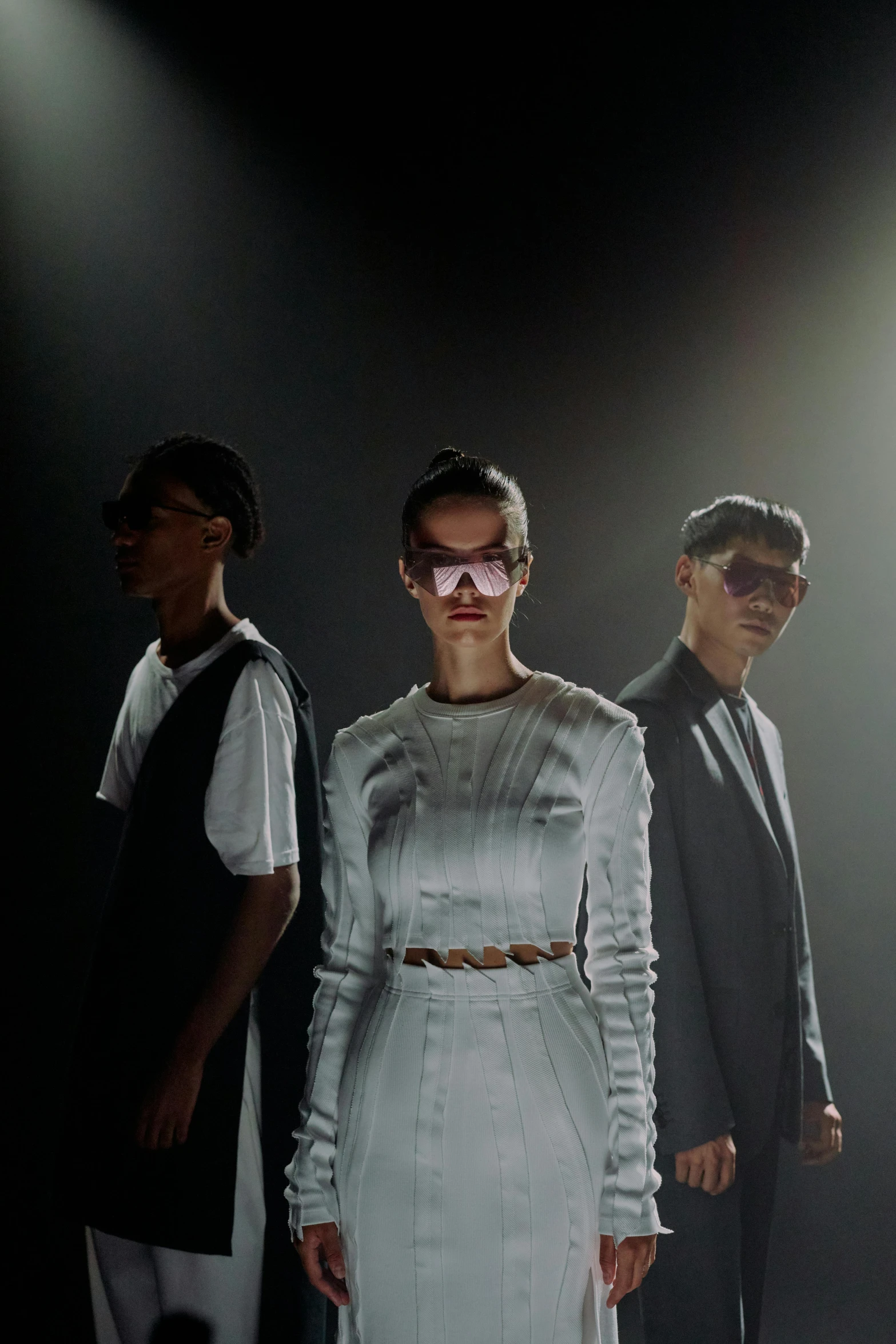 a group of people standing next to each other on a stage, a hologram, bauhaus, fashion shoot, aviators, tense look, a very macular woman in white